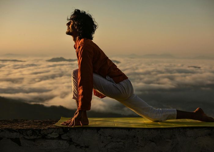 Silhouette of a person in a stretching yoga pose at sunrise.